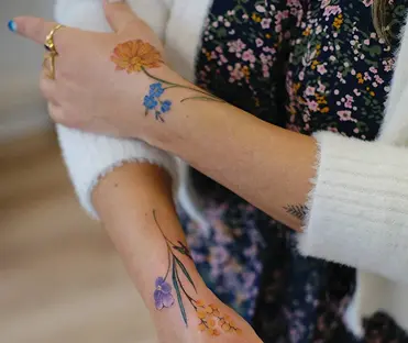 Fine-line floral branch tattoo on the wrist