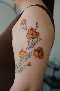 Orange and red floral cluster tattoo on the shoulder