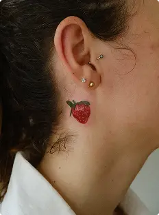 Small strawberry tattoo behind the ear