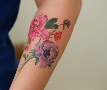 Colorful peony flower tattoo on the inner elbow