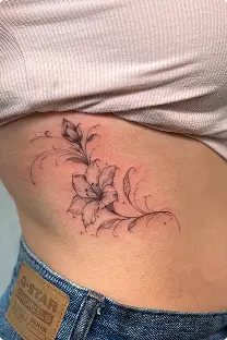 Fine-line floral vine tattoo on the ribs