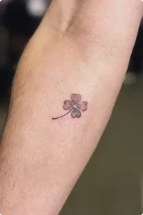 Small four-leaf clover tattoo on the forearm