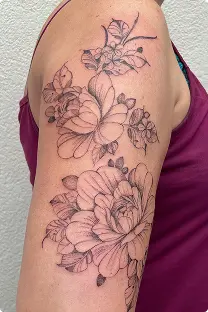 Fine-line cherry blossom branch tattoo on the upper arm